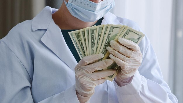 Person in medical attire holding dollar bills